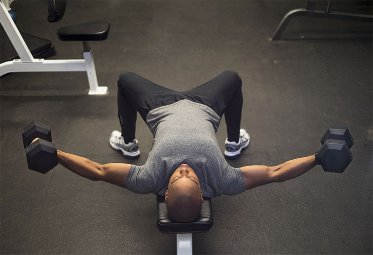 homem realizando o exercício crucifixo com halteres