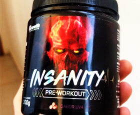 segurando um pote do pré-treino Insanity da Growth Supplements